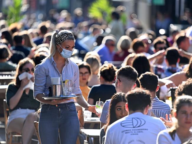 A waitress wearing a protective face covering brings drinks to customers in the late summer sunshine at outside tables in Soho, central London on September 20. Picture: AFP