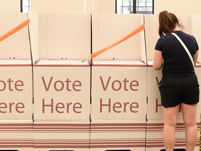 A voter marks ballots at Brisbane City Hall in Brisbane, Saturday, March 28, 2020. Queensland local government elections will be held for mayors and councillors across Queensland's 77 councils. (AAP Image/Albert Perez) NO ARCHIVING