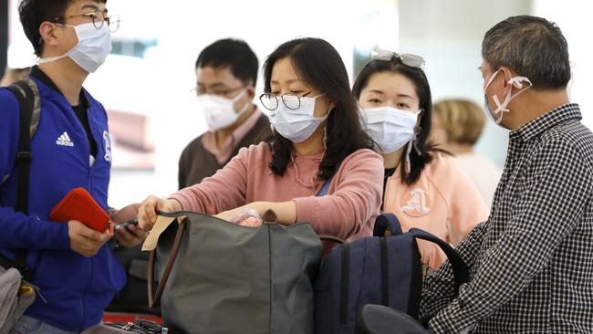 People wearing masks due to coronavirus walk out of Customs after arriving in Sydney from Shanghai. Picture: Chris Pavlich