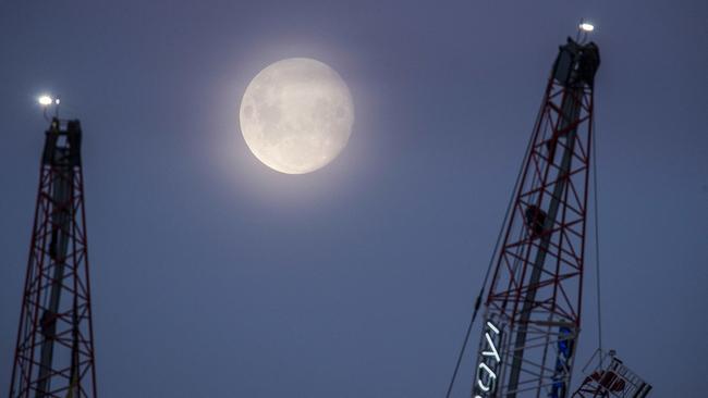 A full moon rises over construction cranes in Melbourne CBD. Picture: Eugene Hyland