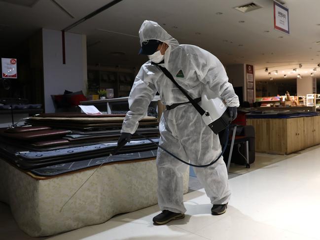 A disinfection professional, wearing protective gear, sprays antiseptic solution around a department store to guard against the coronavirus in Seoul, South Korea. Picture: Getty