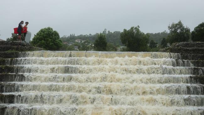 Floodwaters cascade from Flooded Gum Park at Pacific Pines. Picture: Glenn Hampson