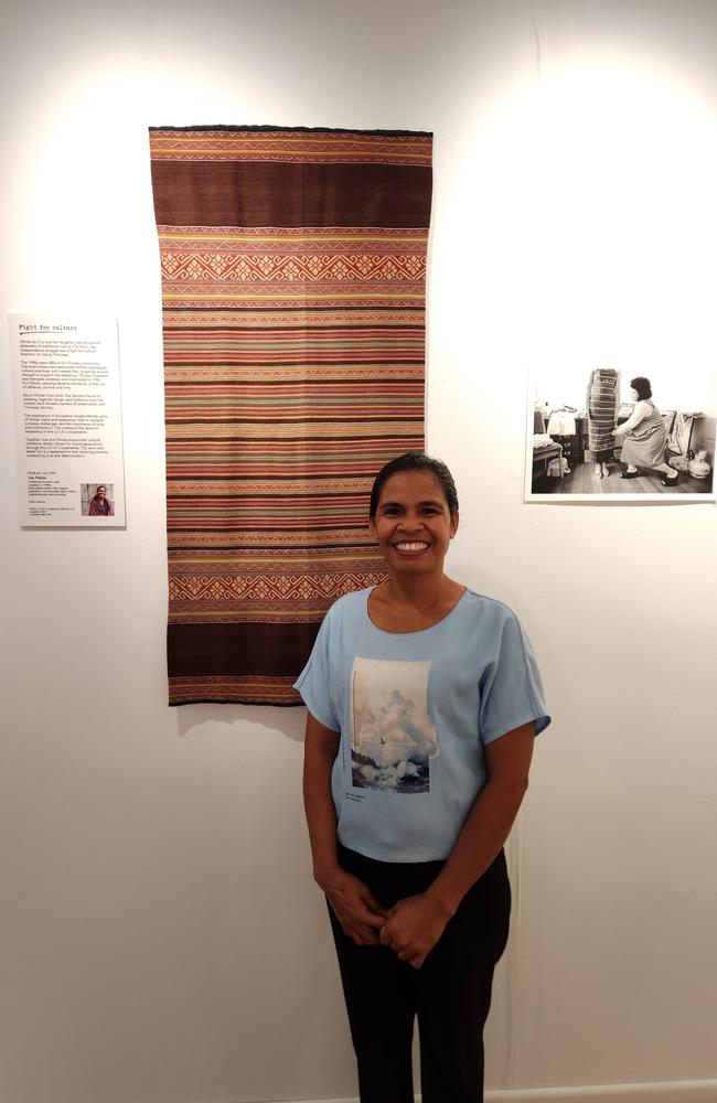 Ilda da Cruz standing in front of a Tais her mother wove.