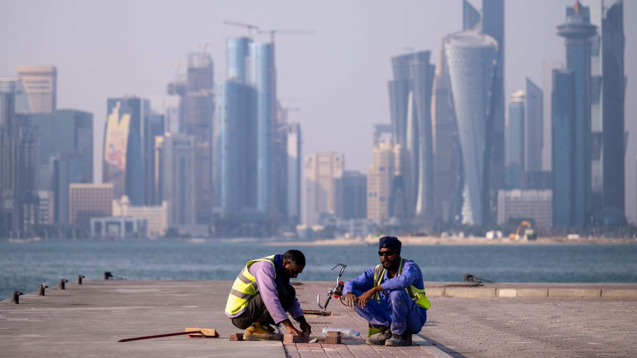 Labourers work near the FIFA World Cup countdown clock in Doha on October 25, 2022, ahead of the Qatar 2022 FIFA World Cup football tournament. (Photo by Jewel SAMAD / AFP)