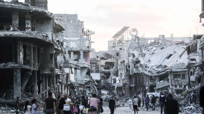 Displaced Palestinians walk between buildings destroyed in Israeli bombardment in Khan Yunis in the southern Gaza Strip (Photo by AFP)