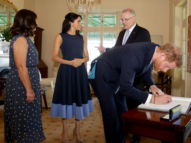 The PM chats to Meghan as Harry signs the visitor’s book at Kirribilli House. Picture: Jonathan Ng Picture: Jonathan Ng