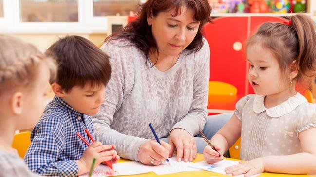 RendezView. Kindergarten teacher, beautiful, mature caucasian woman, brown hair, teaches pupils drawing. Two little girls and a boy. (Pic: iStock)