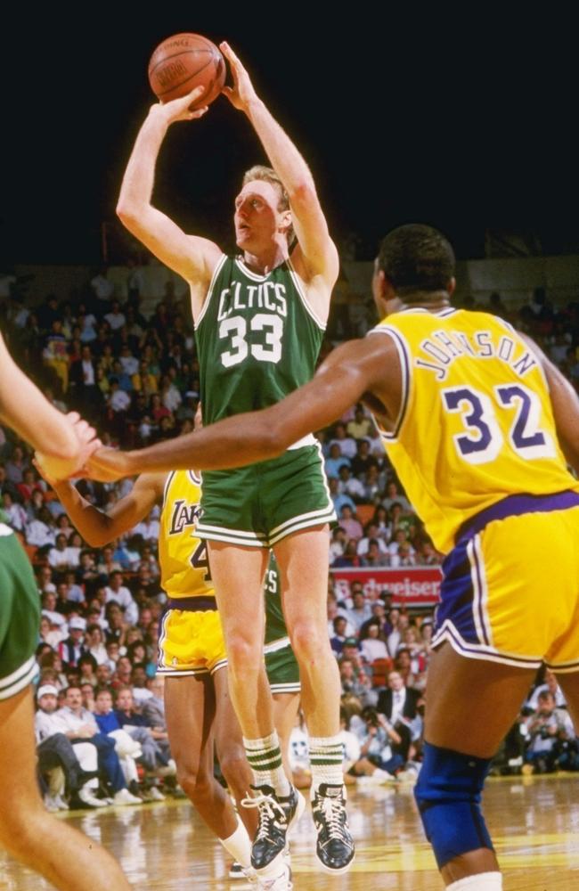 Larry Bird of the Boston Celtics shoots the ball as Magic Johnson of the LA Lakers looks on.