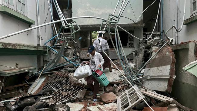 A resident carries belongings over debris next to a damaged building in Naypyidawafter an earthquake in central Myanmar. Picture: Sai Aung Main/AFP