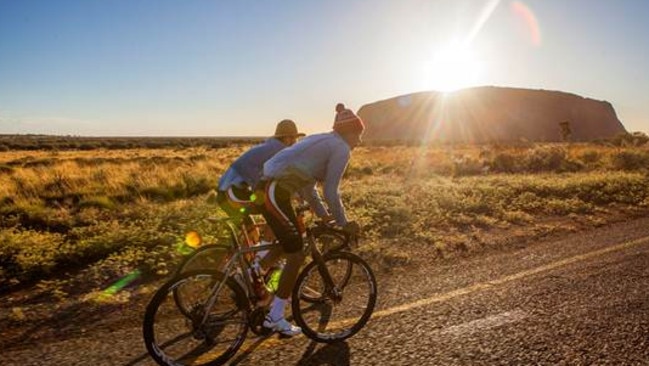 Lachlan and Angus Morton riding past Uluru during their 'Thereabouts' ride in 2013. Picture Scott Mitchell.