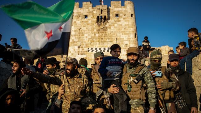 Syrians pose for photographs with rebel fighters at Aleppo’s historic citadel after they successfully overthrew Assad’s rule.