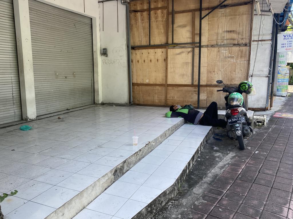 A motorbike rider takes a rest outside a closed shop. Picture: Natalie Wolfe/news.com.au