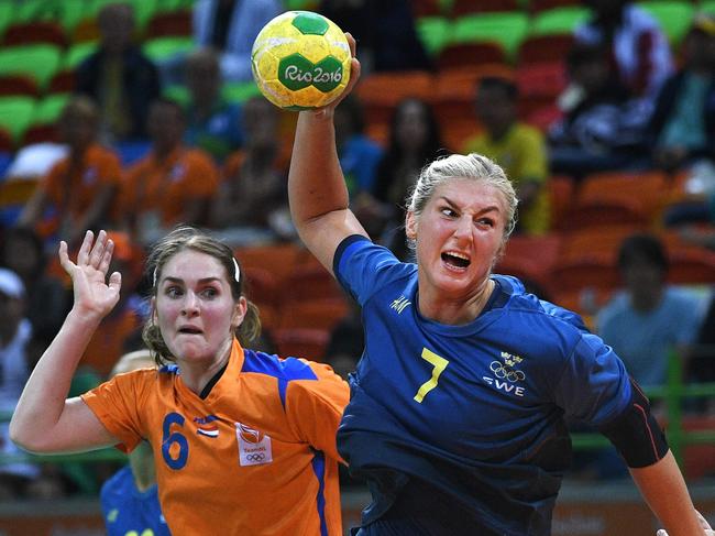 Sweden's pivot Linn Blohm (R) jumps to shoot past Netherlands' right back Laura van der Heijden (C) and Netherlands' left back Kelly Dulfer during the women's preliminaries Group B handball match Sweden vs Netherlands for the Rio 2016 Olympics Games at the Future Arena in Rio on August 12, 2016. / AFP PHOTO / Roberto SCHMIDT