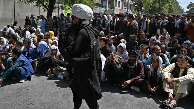 A Taliban fighter keeps an eye on people waiting to withdraw money from a bank in Kabul’s Shar-e-Naw neighborhood on Saturday. Picture: AFP