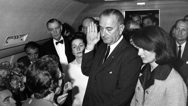 Lyndon Johnson takes the presidential oath of office on Air Force One as wife Lady Bird (left) and Jackie Kennedy (right) look on. Picture: Supplied