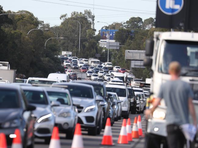 Daily Telegraph January 24/1/23. Traffic buildup on Homebush Bay Drive . Police at the scene of a double fatal crash. Police were pursuing a Audi car when it lost control at the M4 on-ramp  at Homebush from Homebush Bay Drive going through a safety barrier and rolling down a steep embankment onto the M4 before bursting into flames ,killing the two people inside .picture John Grainger