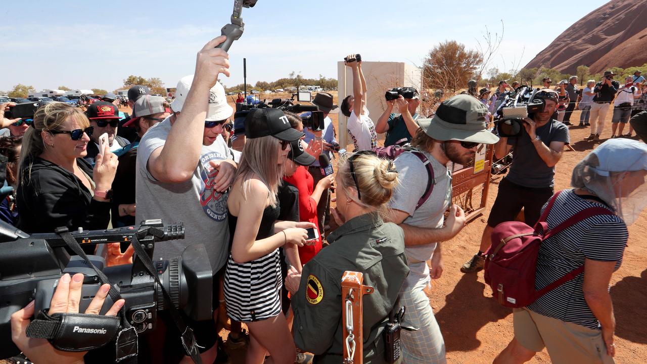 A ranger opens the gate as hundreds of people head up the Uluru climb. Picture: David Geraghty