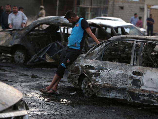 Deadly attacks ... Iraqi men gather at the scene of a car bombing in Baghdad. Picture: AFP