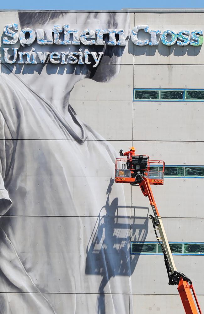 World-renowned large/scale artist Guido van Helten painting the 10-storey building at Southern Cross University Gold Coast campus. Picture: Nigel Hallett.