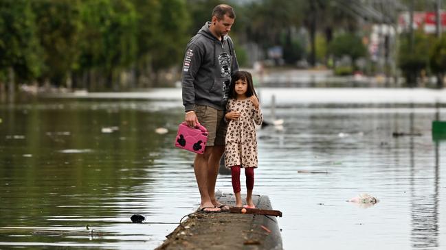 A father and his young daughter inspect a flooded street in Lismore. Picture: Getty Images