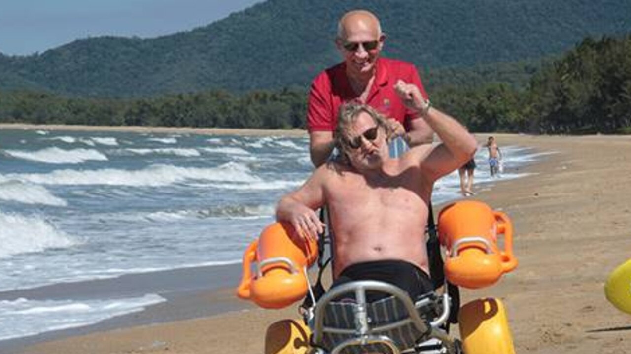 Mayor Bob Manning helps Chris Wighton with the float chair along the beach at Palm Cove. Picture: Supplied.