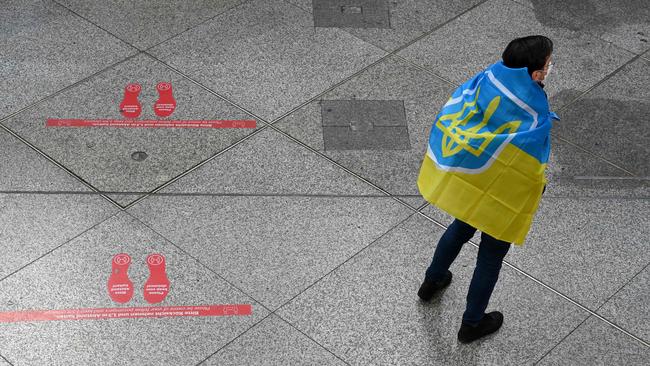 A volunteer wearing a Ukrainian flag waits for the arrival of refugees in a reception hall of the main train station in Munich, southern Germany. Picture: AFP