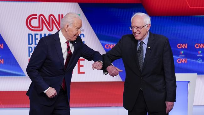 Joe Biden and Bernie Sanders go the pandemic bump ahead of their last debate. Picture: AP