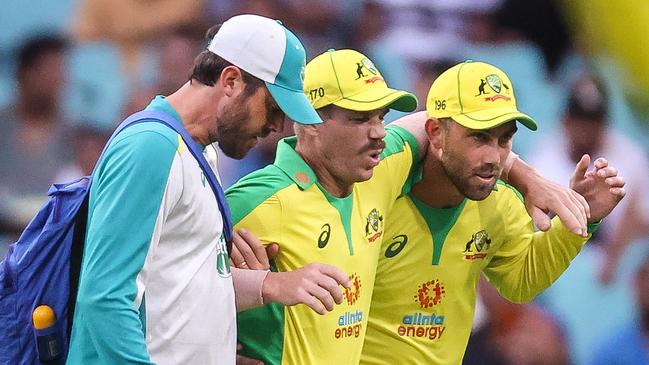 David Warner is assisted by teammate Glenn Maxwell, right, and a trainer at the Sydney Cricket Ground