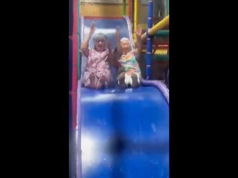 Grandmas show kids how it's done on ball pit slide