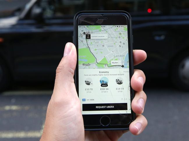 A woman poses holding a smartphone showing the App for ride-sharing cab service Uber in London on September 22, 2017. London transport authorities announced today they would not renew Uber's licence to operate in the city when it expires on September 30 for safety reasons, although it has three weeks to appeal. / AFP PHOTO / Daniel LEAL-OLIVAS