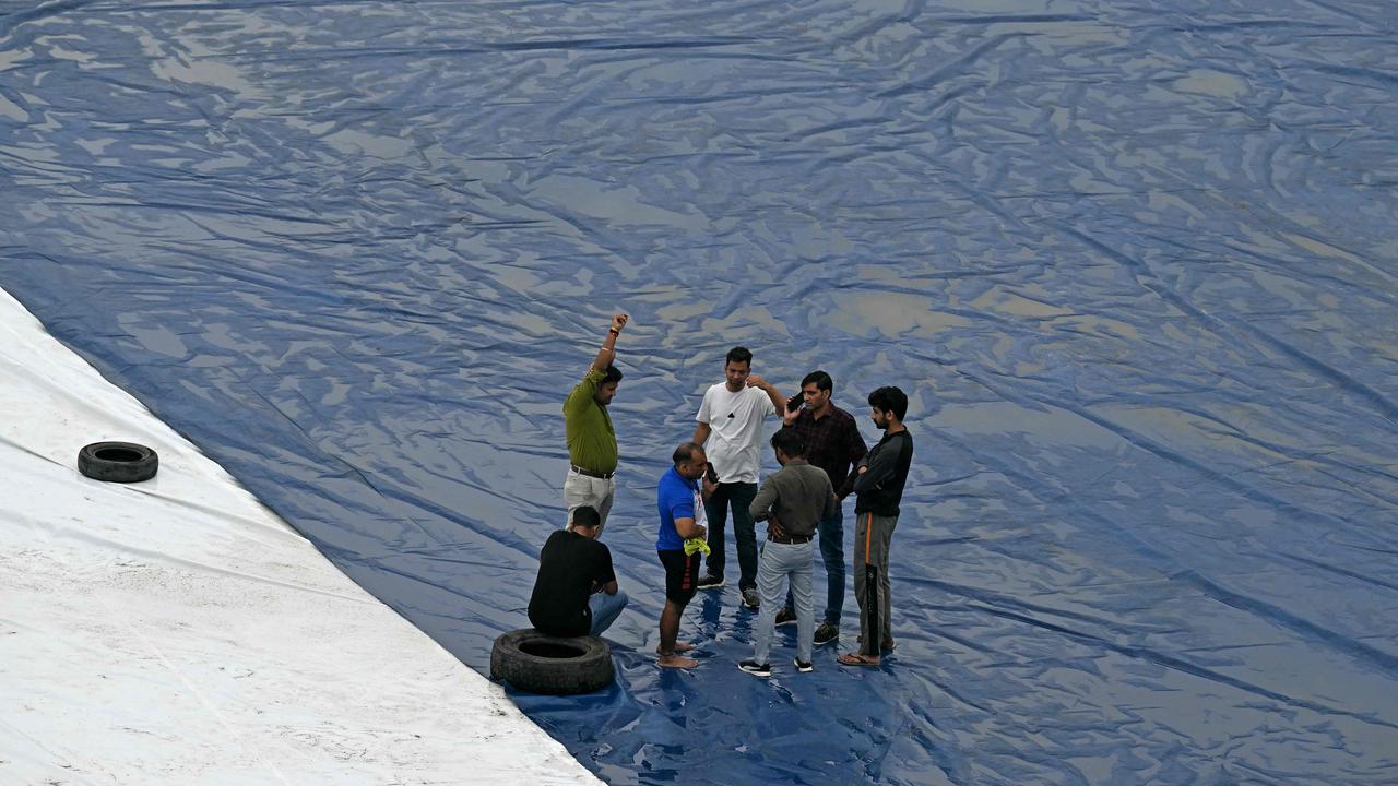 Groundsmen stand over the covered field. Photo by Money SHARMA / AFP