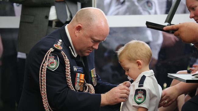 RFS Commissioner Shane Fitzsimmons, who posthumously awarded Geoffrey Keaton with the Commissioner’s Commendation for Extraordinary Service and a Commendation for Bravery, and pinned one of the medals on his son Harvey. Picture: RFS NSW