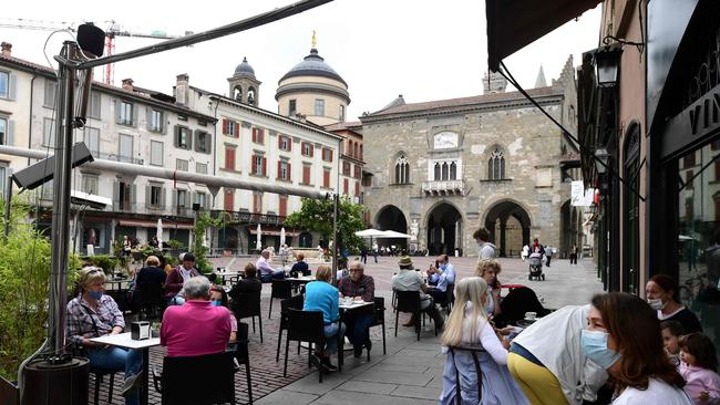 People sit at a cafe's terrace on the Piazza Vecchia in the upper city of Bergamo as Italy eases lockdown measures.