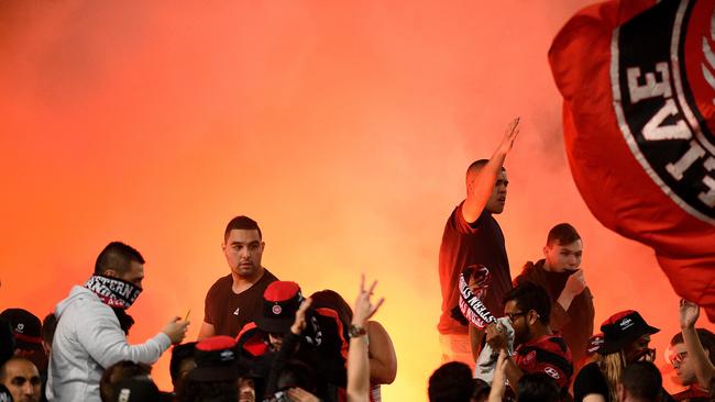 Wanderers supporters in the Red and Black Bloc light a flare.