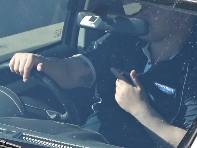 A person in the drivers seat of their car on their phone while at a set of traffic lights, Warringa Road, Frenchs Forest, Sydney. 24th September, 2019. Picture by Damian Shaw