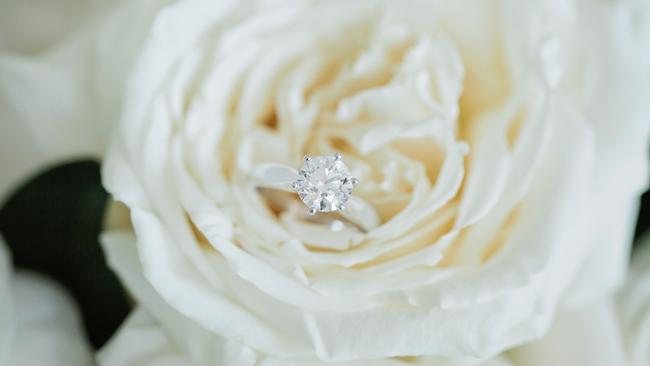 Bit of sparkle: Kelly Gaffney’s solitaire engagement ring nestles gently on a white rose, photography: Quince and Mulberry Studios