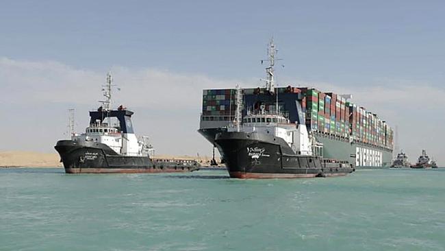 Tugboats guide the Panama-flagged MV Ever Given container ship after it was fully dislodged from the banks of the Suez Canal. Picture: AFP