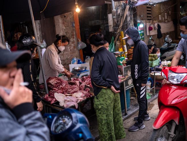 People wear face masks amid concerns of the spread of the COVID-19 coronavirus while shopping at a local market on in Hanoi, Vietnam.