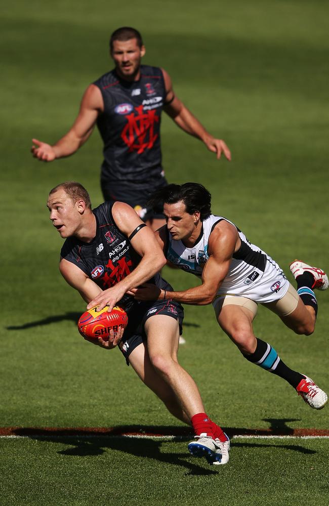 Dean Terlich tries to handball before being tackled by Port Adelaide’s Kane Mitchell.