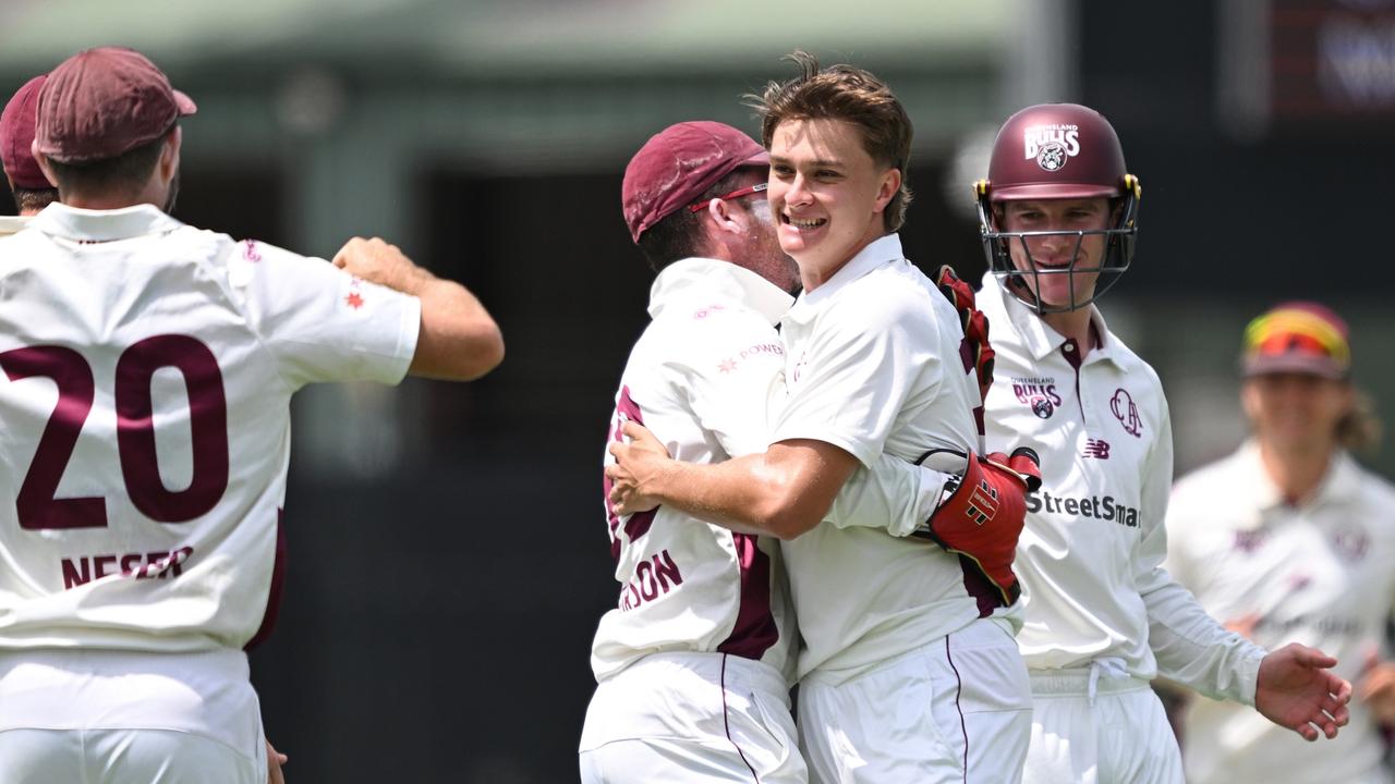 Queensland teammates celebrate with debutant bowler Tom Whitney after he claimed his fifth wicket on the second day of the Sheffield Shield clash against South Australia at Allan Border Field. Picture: Bradley Kanaris / Getty Images