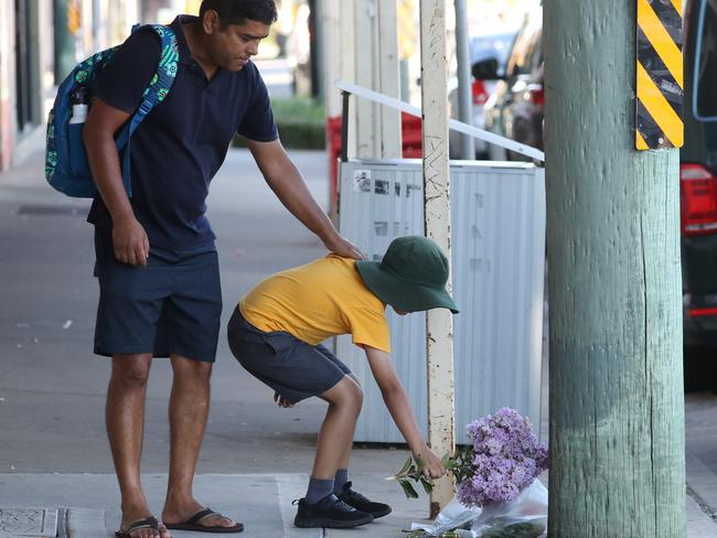 A young boy lays flowers with his dad at the scene on Railway Parade, Glenfield. Picture John Grainger