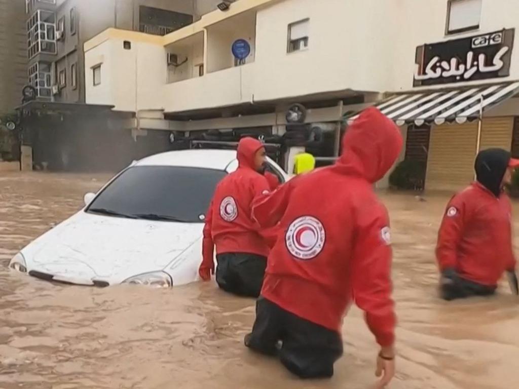 Red Cross team members assisting drivers whose cars are engulfed in floods in al-Bayda town in eastern Libya. (Photo by Basma BADRAN / Libyan Red Crescent / AFP)