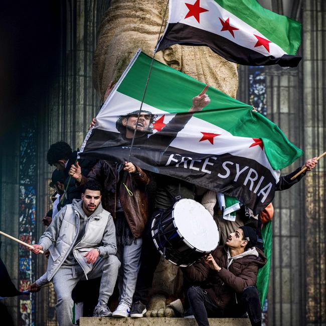 Members of the Syrian community wave Syria's national flags during a demonstration near Domplein to celebrate the end of the regime of Syrian dictator Bashar al-Assad after rebel fighters took control of the Syrian capital Damascus.