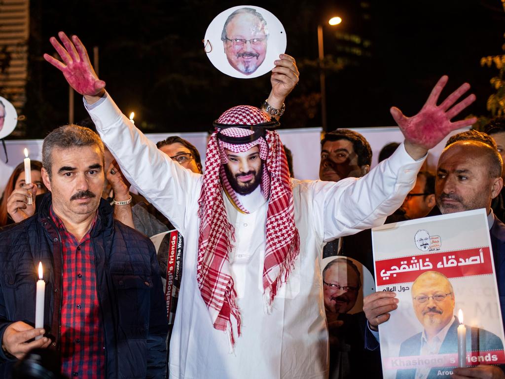 A protester wears a mask of depicting Saudi Crown Prince Mohammad bin Salman with red painted hands next to people holding posters of Khashoggi outside the Saudi Arabia consulate in Istanbul. Picture: AFP