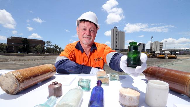 Archaeologist Dr Kevin Rains holds a bottle of The Crown perfume, above other artefacts found during Cross River Rail excavation. Picture: AAP Image/Richard Gosling