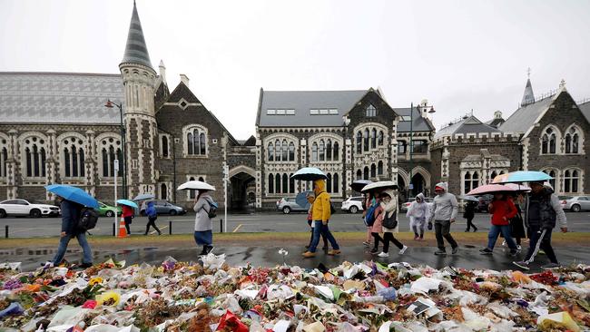 People walk past flowers and tributes displayed in memory of the twin mosque massacre victims outside the Botanical Gardens in Christchurch on April 5, 2019. Picture: AFP