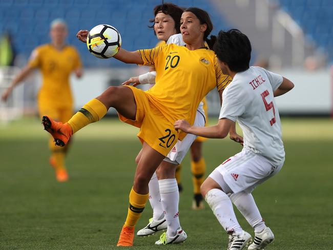 Samantha May Kerr of Australia kicks the ball under pressure from Muzuho Sakaguchi (L) and Nana Ichise (R) of Japan during the AFC Women's Asian Cup Group B match between Japan and Australia.