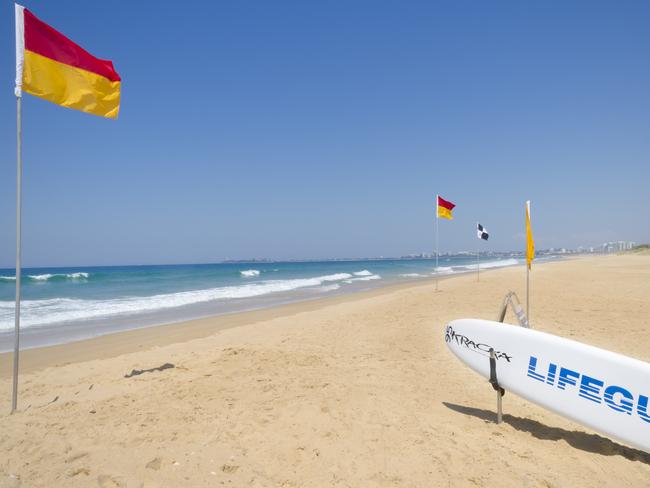 Twin Waters North Shore, Australia - September 22, 2012: Image features Surf life saver red and yellow flags and lifeguard surfboard on beach.