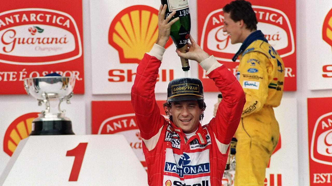 Senna celebrates another podium as Schumacher smiles in the background. (Photo by Julio Pereira/AFP)