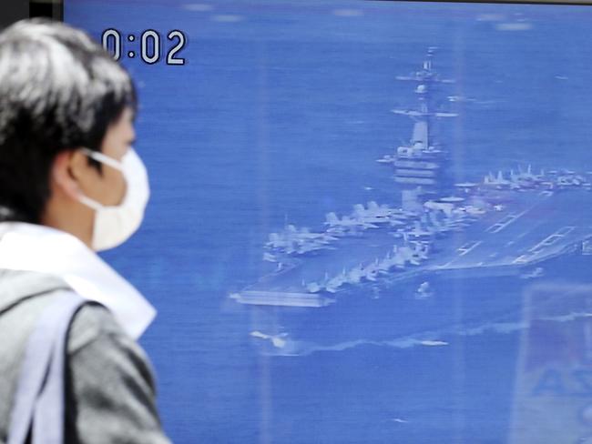 A man walks past a TV news showing an image of USS aircraft carrier Carl Vinson while reporting North Korea's missile test, in Tokyo. Picture: AP